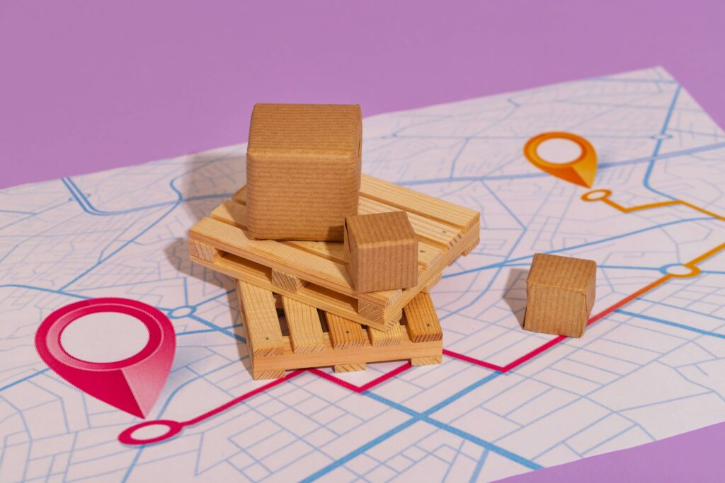 Miniature cardboard packages and wooden pallets placed on a route map, symbolizing common shipping challenges and delivery planning.